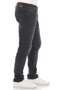 Svarta denimjeans med slim fit, med en standard midja, fem fickor och en subtil blekt textur. Bärs med vita sneakers.