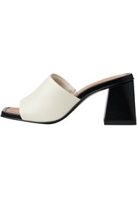 Scarpa slide open-toe realizzata in pelle color crema con tacco a blocco nero. Presenta una superficie liscia e un design minimalista.