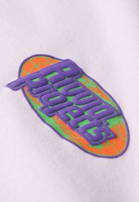 Fialový vyšívaný nápis "Rivulet Projects" se zeleným lemováním na světle fialovém látkovém pozadí, zdobený oranžovým návrhem planety.