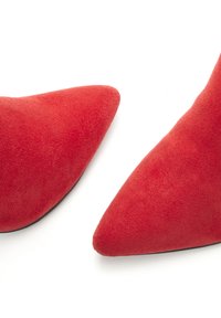 Red suede pointed-toe shoes with a smooth texture, featuring a sleek design and black soles. No visible hardware or patterns.