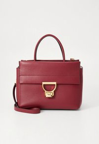 Raudonos odos rankinė su struktūruota forma, viršutinėmis rankenomis ir nuimamu petnešos dirželiu. Yra aukso spalvos metalinės sagtys ir vertikalios siūlės detalės.