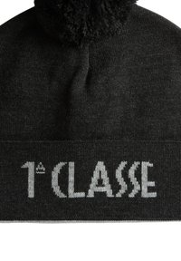 Berretto a cuffia nero in maglia con un pon pon testurizzato sulla sommità, caratterizzato da testo ricamato grigio "1ère CLASSE" sulla banda ripiegata.