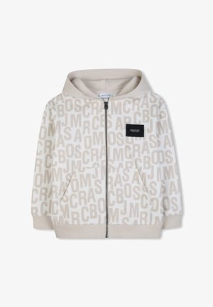 Sweat à capuche beige zippé avec un motif répétitif "MARC JACOBS" sur l'ensemble et une petite étiquette de marque noire rectangulaire sur la poitrine.
