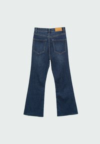 Jean en denim bleu foncé avec une taille haute, deux poches arrière, des jambes légèrement évasées et un patch de marque en cuir marron à la taille.