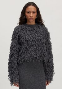 Chunky grijze gebreide trui met lange franjes, ronde halslijn en verlaagde schouders, gecombineerd met een bijpassende slim-fit grijze rok.
