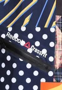 CrossFit-väska med marinblått tyg, gula ränder, vita prickar och en dragkedjeficka. Inkluderar "Reebok CrossFit"-logotypen i vitt.