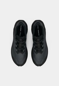 Must jalanijalgade paar musta Salomon'i jooksujalatsit, millel on võrkkangas ja paelad, vaadatuna ülalt valgel taustal.