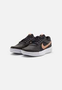 Sneaker nere in pelle con un design perforato, dotate di un logo Nike in rosa oro, suola in gomma bianca e lacci neri.