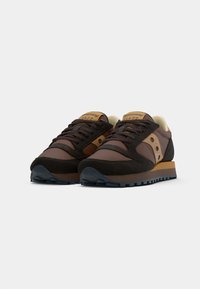 Brune semskede og nylon sneakers med en beige logo, fremtrædende snøring og en tekstureret, kontrasterende gummisåle. Klassisk, lavprofil design.