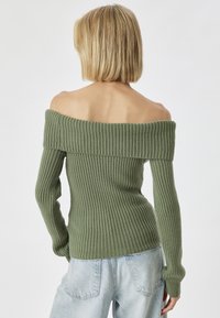 Olivenfarbener Rippstrickpulli mit schulterfreier Silhouette, langen Ärmeln und enganliegendem Design. Weiche Textur mit weitem Halsausschnitt.