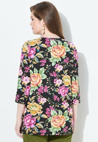 Schwarze Blumentunika mit lebhaften rosa, gelben und grünen Blumen. Verfügt über Dreiviertelärmel und eine lockere Passform. Glattes, leichtes Gewebe.
