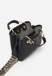 Czarna skórzana torebka o fakturowanej powierzchni, z złotymi elementami i odpinanym paskiem ozdobionym logo. Otwarty design ukazuje jasne wnętrze.