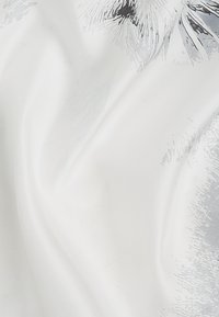 Hvidt stof med en glat tekstur, prydet med et subtilt gråt blomstermønster. Designet er let og gennemsigtigt, hvilket skaber lette folder.