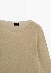 Pull beige en maille avec un col rond, une coupe ample et une texture subtile. Présente des coutures minimales et des étiquettes de marque à l'intérieur du col.