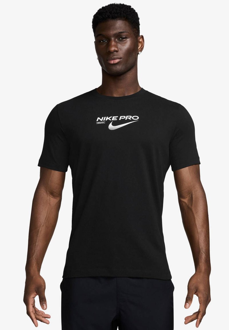 Svart Nike Pro t-skjorte med kort erme laget av mykt stoff, med en hvit Nike-logo og tekst over brystet, i en klassisk passform.
