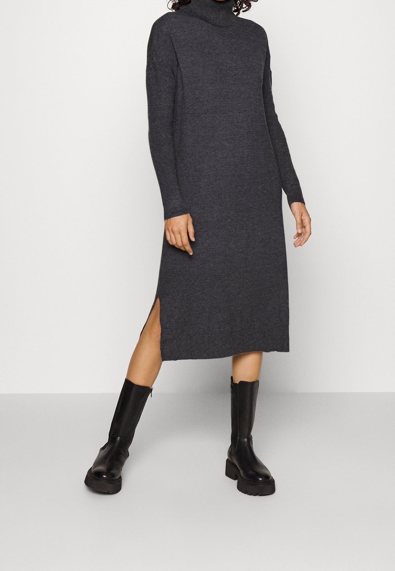 Szara dzianinowa sukienka z golfem, długimi rękawami i bocznymi rozcięciami, połączona z czarnymi skórzanymi botkami dociążonymi na podeszwie i z zamkiem.