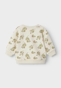 Kremveida kokvilnas sporta krekls ar botānisku apdrukājumu, kas attēlo zaļas un brūnas lapas. Ar ribotām piedurknēm un apakšmalu, kā arī apaļu kakla izgriezumu.