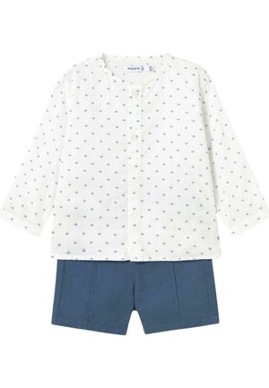 Camisa blanca de manga larga con patrón de puntos azules y cierre de botones, combinada con pantalones cortos azul marino con pliegues delanteros.