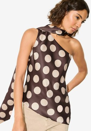 Nő, barna szatén egyvállas felsőt visel nagy, bézs pöttyökkel és hozzá illő sállal, bézs nadrággal párosítva.