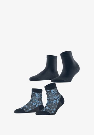 Vier paar sokken: twee effen zwarte enkelsokken en twee gemusterde sokken met een blauw bloemenpatroon op een donkere achtergrond.