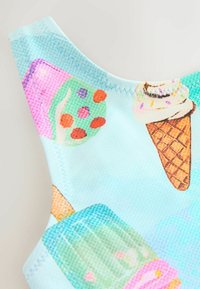 Jasnoniebieska tkanina z nadrukiem rożków lodów, lodów na patyku i ozdobnych ciasteczek. Charakteryzuje się żywymi kolorami i drobnym haftem wzdłuż dekoltu.