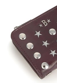 Portefeuille en cuir bordeaux avec des clous en argent et des accents en forme d'étoile, doté d'une finition lisse et texturée, et d'un fermoir en métal.