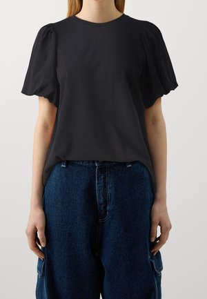 Sort kortærmet bluse med puffede ærmer, rund halsudskæring og en afslappet pasform, kombineret med højtaljede blå denimbukser.