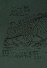 Camiseta verde oscuro con arte gráfico lineal negro que representa crestas montañosas, con el texto: "SISTEMAS DE GLACIAR", "CRESTA DE FROST", y más.
