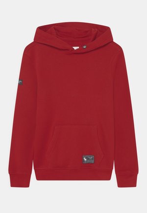 Rotes Kapuzensweatshirt mit vorderer Kängurutasche und kleinen aufgenähten Logo-Patches an der unteren Tasche und am linken Ärmel.