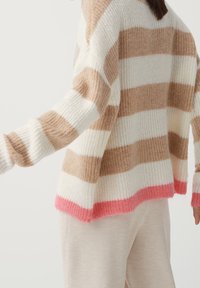 Beige och krämfärgad randig tröja i en mjuk, texturerad stickning, med en klar rosa nederkant. Lös passform med sänkta axlar och långa ärmar.