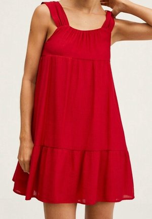 Mujer con vestido corto sin mangas de color rojo brillante, con escote cuadrado y detalle de tela fruncida en el pecho.