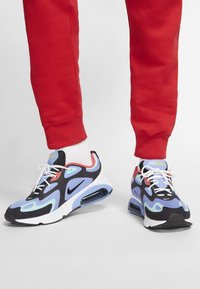 Nike Air Max 200 sneakers in black, blue, and red with white accents; features a textured upper and visible air cushioning in the sole.
