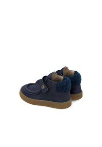 Scarpe in pelle blu navy con un colletto in maglia blu testurizzata, punta rotonda e strap in Velcro. Suola in gomma con una finitura marrone chiaro.