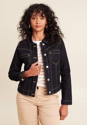 Zwarte denim jack met gouden stiksels, voorzien van voorzakken en drukknoopsluitingen. Draag het over een gestreept shirt, gecombineerd met beige broek.