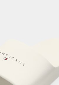 Hvit sklifri sandal med matt finish, med en fremtredende "TOMMYJEANS" logo og en geometrisk aksent i rød og blå.