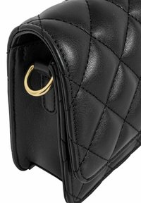 Czarna skórzana torebka z pikowanym wzorem, o zaokrąglonym kształcie i złotych akcentach hardware. Teksturowana powierzchnia z widocznymi detalami szwów.