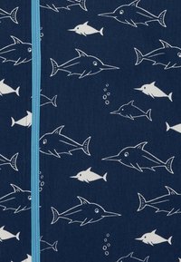 Tessuto blu navy con illustrazioni di pesci bianchi, tra cui pesci spada e altri pesci piccoli, con un dettaglio di zip azzurro chiaro al centro.