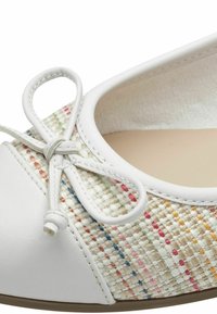 Ballerines blanches avec un dessus tissé et des accents multicolores, bout rond et détail de nœud décoratif à l'avant.