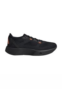 Black athletic shoes with a textured mesh upper, orange accents, flat laces, and a thick black sole featuring a subtle logo detail.