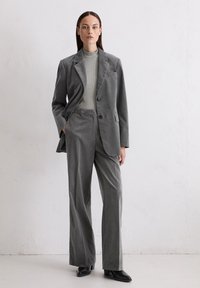 Gray corduroy suit with a tailored blazer and wide-leg trousers, paired with a light gray fitted top and black heeled shoes.