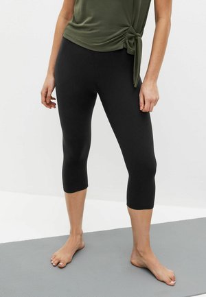 Sorte capri leggings lavet af strækbart materiale med en glat tekstur, der har et tætsiddende design, som går til lige under knæet.