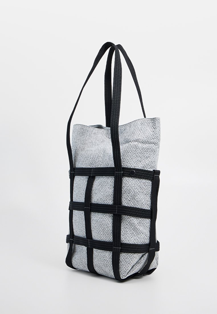 Graue Stofftasche mit schwarzen Akzenten, die ein gitterartiges Design aufweist und zwei mittelgroße Tragegurte zum Tragen hat. Glatte Textur.