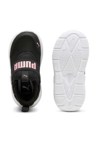 Zapatilla infantil Puma en negro y rosa con parte superior de malla, correa elástica y suela blanca texturizada, mostrada desde vistas superior e inferior.
