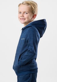 Marinblå zip-up hoodie i mjukt material, med ett texturerat mönster, framfickor och en huva med dragsnören.