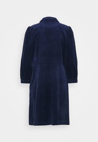 Mekko tummansinisestä vakosamettikankaasta, varustettuna kauluksella, pitkillä puffi-hihoilla ja suoralla siluetilla. Mekossa on teksturoitu kangas ja se ulottuu yli polven.