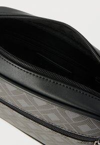 Μαύρη τσάντα από συνθετικό δέρμα με εξωτερικό γκρι μοτίβο. Κλείσιμο με φερμουάρ και εσωτερική επένδυση από ύφασμα. Διαθέτει επιπλέον εσωτερική τσέπη.