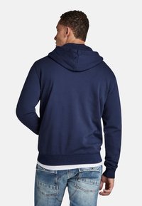 Navy blue hooded sweatshirt made of soft cotton blend, featuring a ribbed hem, and cuffs, with a smooth texture and subtle stitching details.