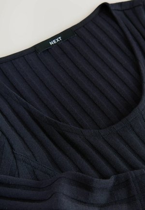 Donkerblauwe ribstof ligt plat, met een ronde halslijn en een zichtbare label met de tekst "NEXT" nabij de kraag.