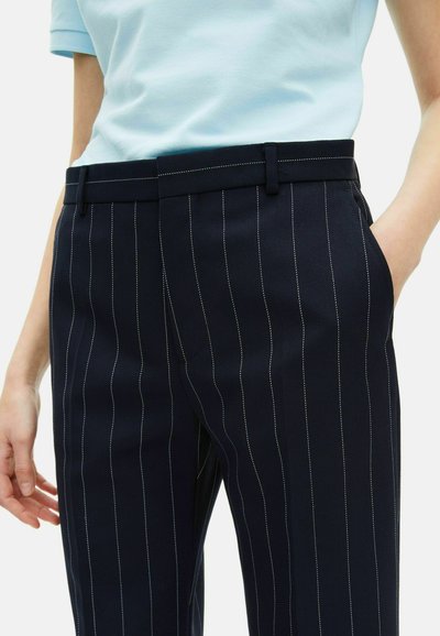 Pantaloni a righe blu navy realizzati in tessuto testurizzato, con una vestibilità su misura, due tasche laterali e cuciture bianche a contrasto sui bordi.