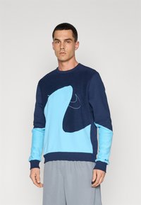 Sweatshirt azul marinho e claro com um grande design abstrato, punhos canelados e decote redondo, feito de tecido suave e texturizado.